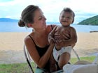 Lauren Goodwin, a Peace Corps Response Volunteer in Malawi, holds a friend's baby at Mangochi beach.