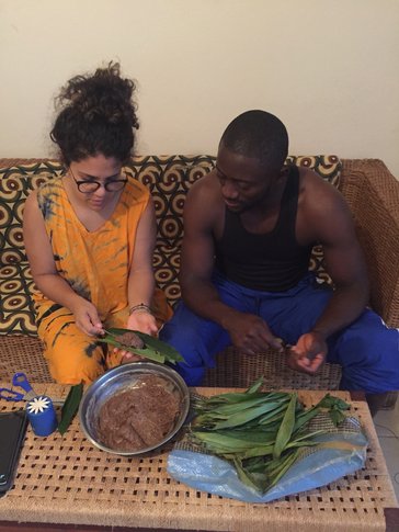 A Puerto Rican woman and Cameroonian man sit on a couch, cooking together