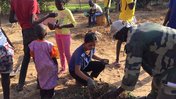 An American woman digs in the dirt with her fellow Senegalese friends