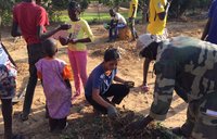 An American woman digs in the dirt with her fellow Senegalese friends