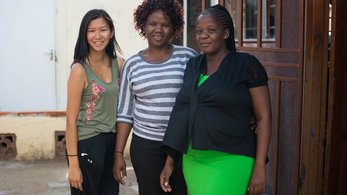 An Asian-American female stands outside in the sun with her friends in Botswana