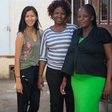An Asian-American female stands outside in the sun with her friends in Botswana