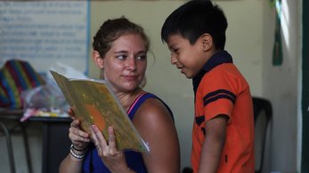 A PCV reads to a young student.