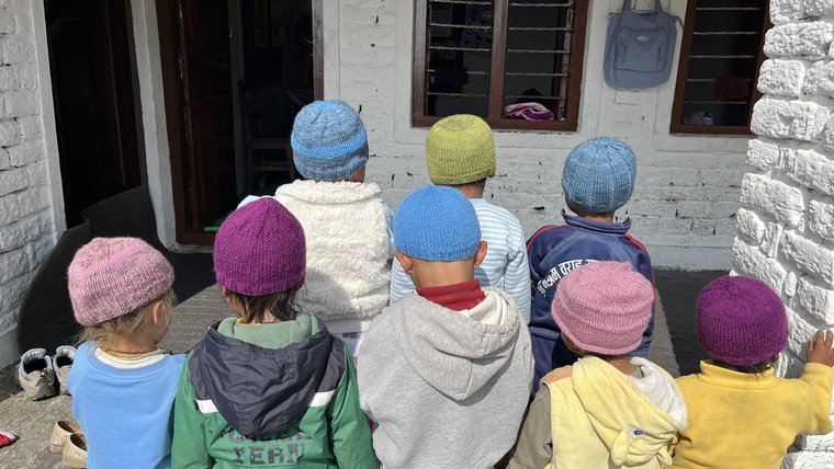 Children wear hats Karen knitted at the community childcare center.