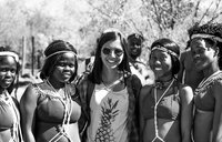 A Asian American female stands with her friends who are wearing traditional dress. Photo in black and white.