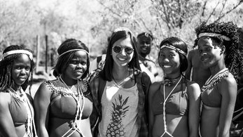 A Asian American female stands with her friends who are wearing traditional dress. Photo in black and white.