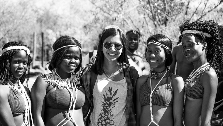 A Asian American female stands with her friends who are wearing traditional dress. Photo in black and white.