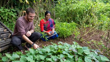 A Volunteer works in a garden with a community member in Nepal.