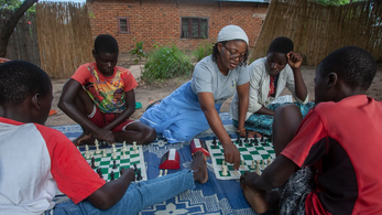 Host Country National, Susan, teaches chess to youth. Susan received a chess board when she was a girl from a Peace Corps Volunteer.