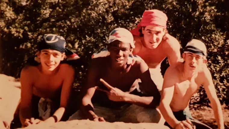 Four people in front of tree sitting on rock