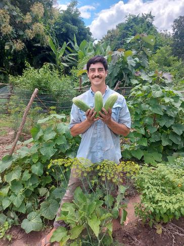 Austin shows off cucumbers grown by students in a school garden in Ghana.