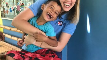 A PCV and student laugh together