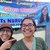An Asian-American female Volunteer stands next to her Indonesian host mom and smiles in front of a banner with her face on it