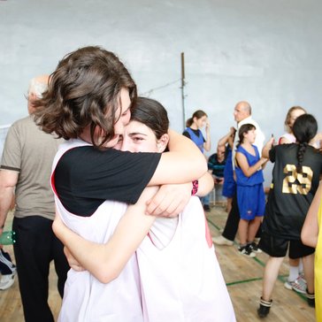 Two basketball players embrace after an emotional win.