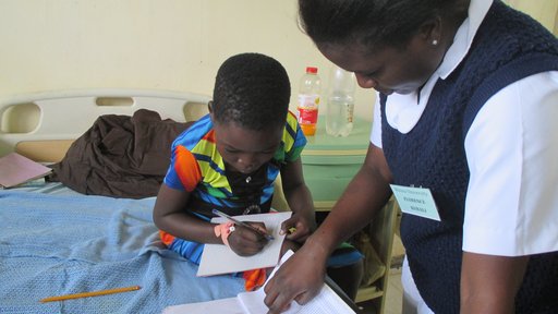 Florence, a nursing student, with Agnes, explaining the lesson book in Chichewa