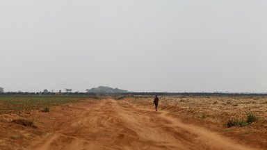 A bare dusty dirt road leads off into a flat, treeless land