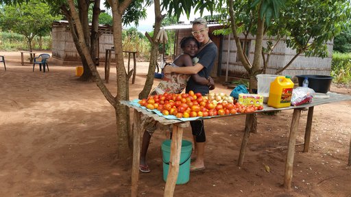 Blonde, white American hugs Mozambican friend in a market.