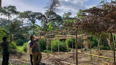 community members and Volunteer Logan build the cocoa nursery structure