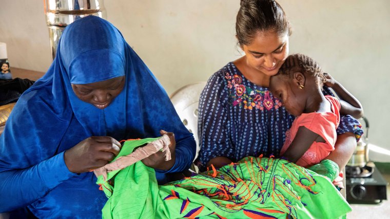 A Volunteer in The Gambia doing needlework with her host family.
