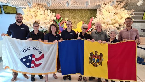 Peace Corps Response volunteer posed in Chisinau airport holding Moldovan and Peace Corps flags. on the day of their arrival to Moldova