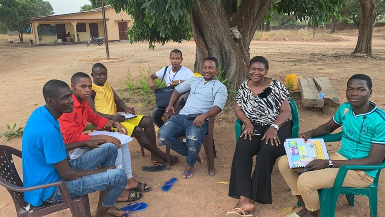 A group of people sitting in chairs around a tree