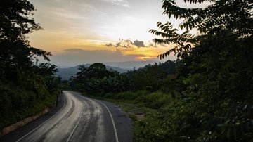 Image of a road with a green and tropical landscape surrounding it.