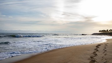 Ocean and beach landscape with footprints in the sand.
