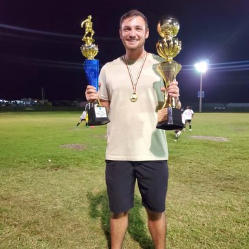 Coach Chance displays trophies from his teams' wins in Guyana.