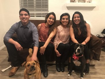 Fiorella's brother, sister, mom, and two dogs sit together on a couch