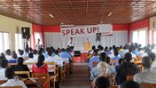 Image taken from the rear of the room with participants seated and Speak Up banner in front of the room