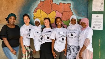 Volunteer and Community Members Pose in Front of a Map During a Menstrual Hygiene Workshop in The Gambia