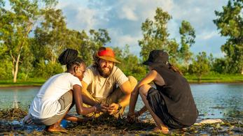 Peace Corps Volunteer Planting Mangroves with Community Members and Smiling