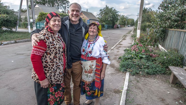 A white American male stands with his Ukrainian friends outside on a road
