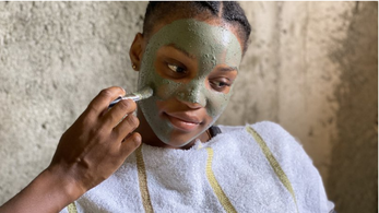 A young black woman has a facemask applied