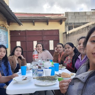 8 women gather around a table of food and soda