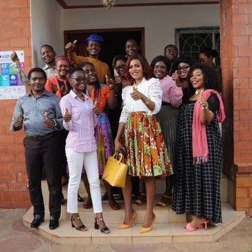 Fourteen individuals smile with thumbs up