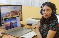 A Mongolian woman wears a headset for a virtual meeting