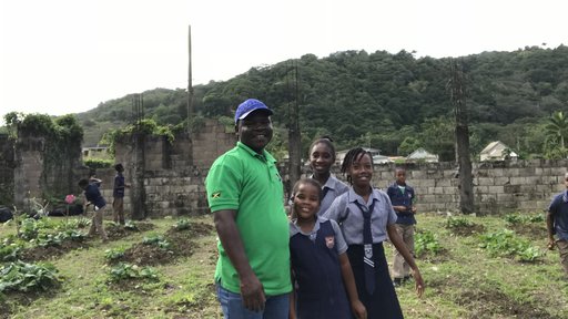 Male Peace Corps Jamaica volunteer from Togo spends time in the garden with his primary school students
