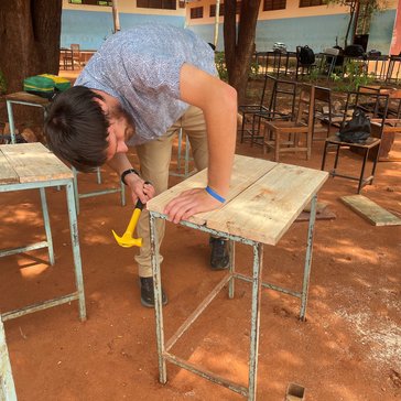 Adam repairs student desks and chairs in collaboration with the school academic office.