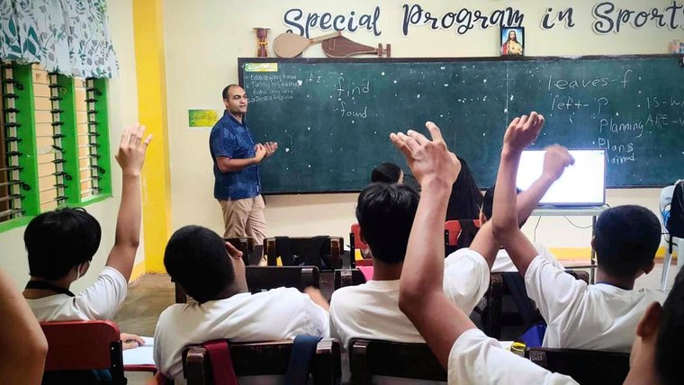 Volunteer teaching a class of students in the Philippines.