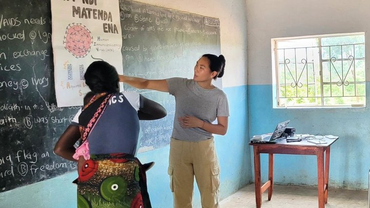 Angelina engages a Zambian student about health issues in the classroom.
