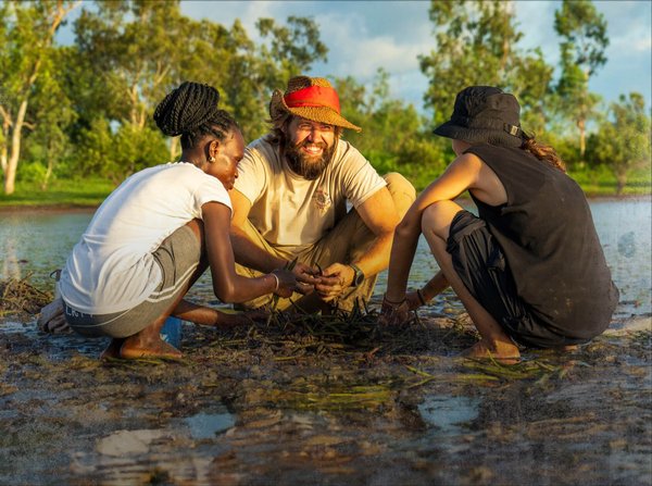 Three people kneeling in mud