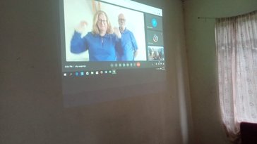An older white couple appears on a projector screen