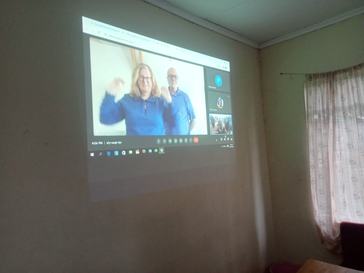 An older white couple appears on a projector screen