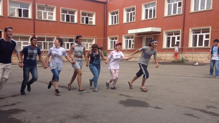 The photo shows students playing a form of tag where teamwork is essential. Both boys and girls join hands in this photo (whi