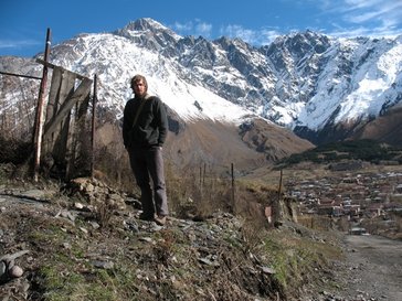 A male hiker stands in front of a snow-covered mountain