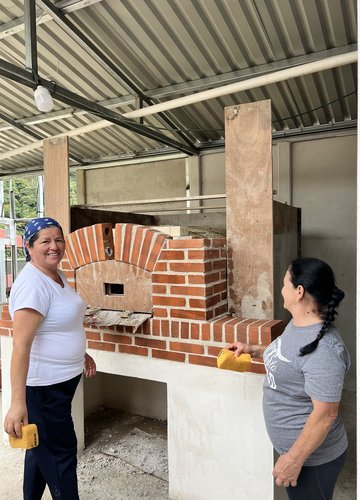 Two members of a Costa Rican women's group work on constructing a new oven with the support of a nonprofit based in Minnesota.