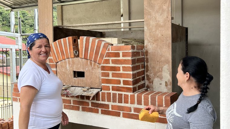 Two members of a Costa Rican women's group work on constructing a new oven with the support of a nonprofit based in Minnesota.