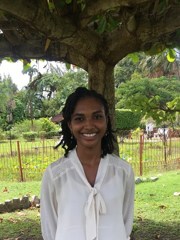 A woman smiles with her hands behind her back