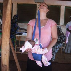 A Peace Corps Volunteer health worker weighs a baby before the baby is vaccinated.